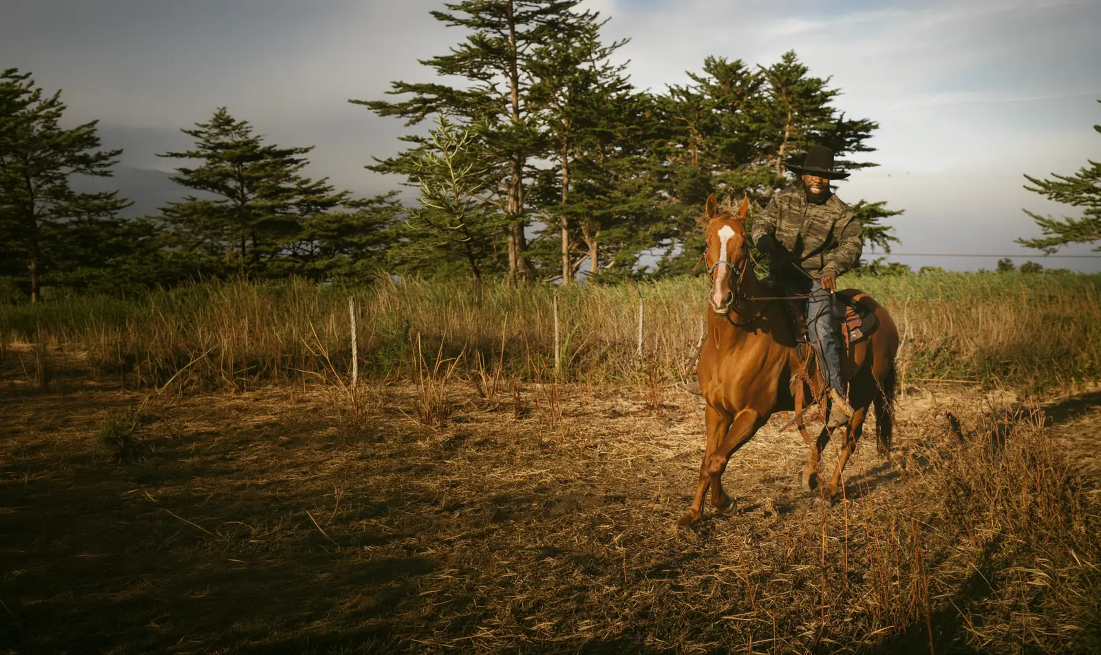 Jibreel riding horseback across the ranch pasture