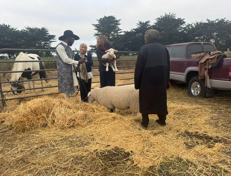 Jibreel with a family at the ranch, holding a lamb